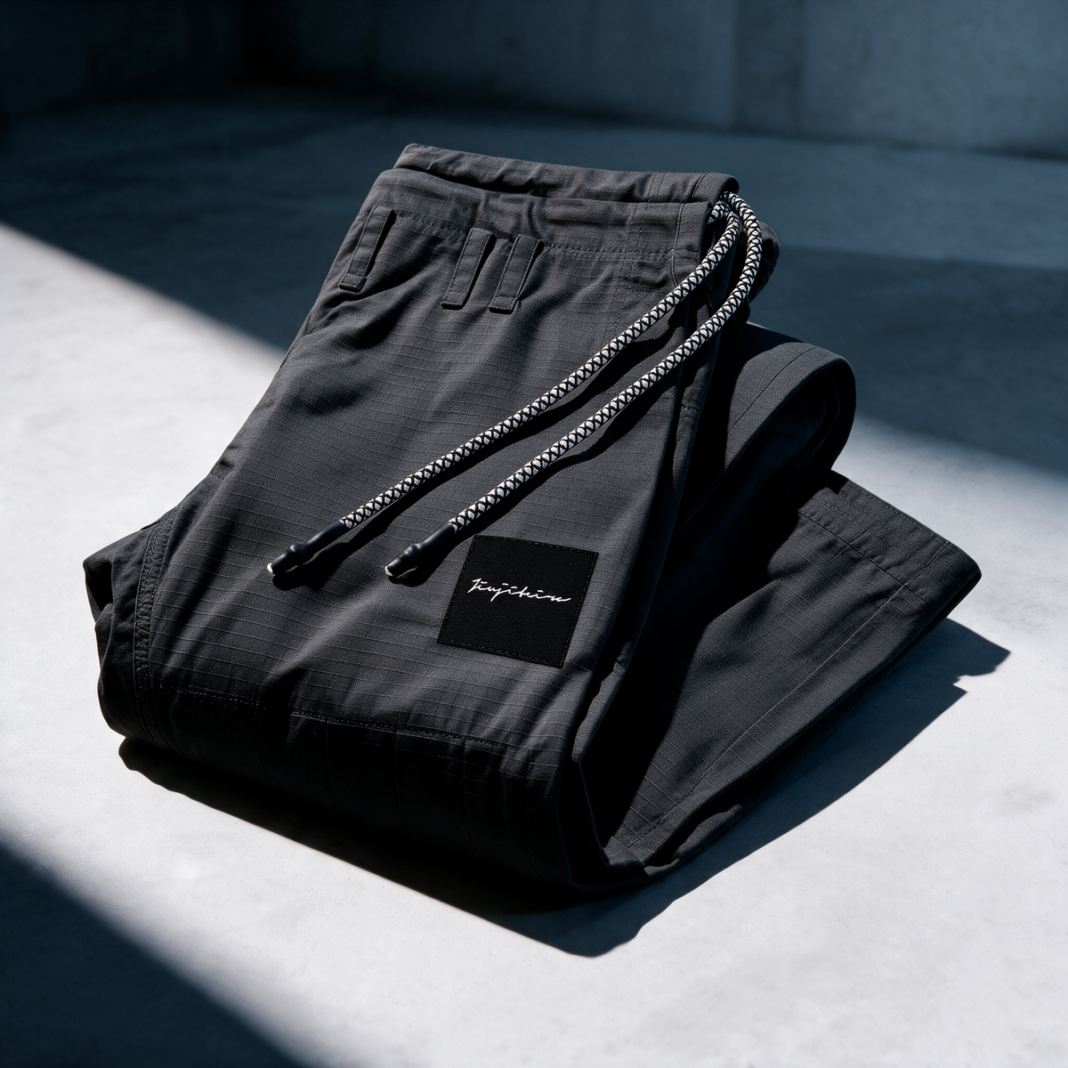 Folded black Jiujiteiro gi pants with drawcord and logo detail